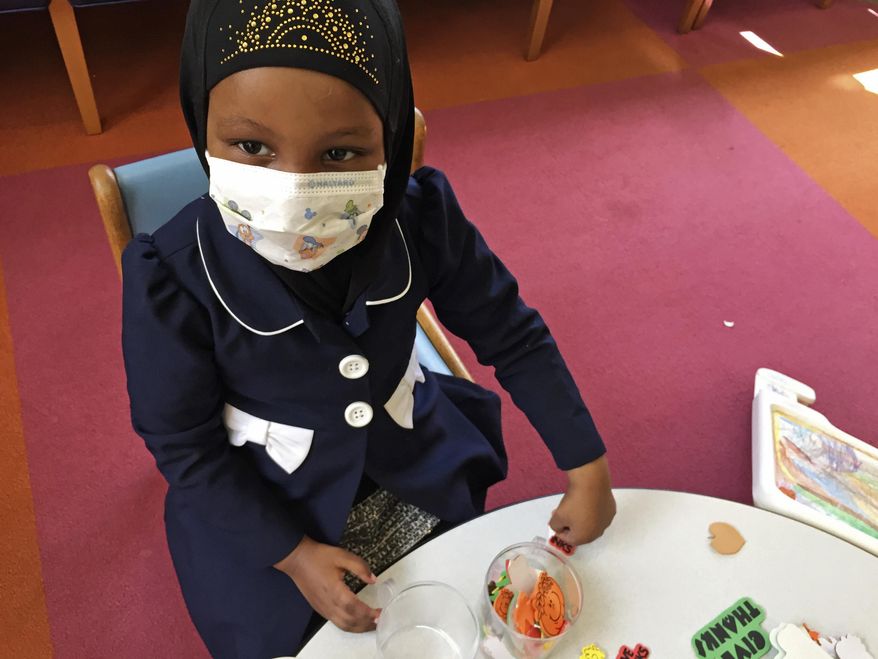 In this Tuesday, May 2, 2017, photo, Amira Hassan, of Burnsville, Minn., plays in the waiting room at the specialty clinic at Children's Minnesota in Minneapolis. Hassan went to the hospital's clinic for a routine wellness check, but had to wear a mask to protect her from measles after an outbreak has sickened more than 30 children in Minnesota. The masks are just one precaution that hospitals are taking to try to control the spread of the disease, which is predominantly affecting Minnesota's Somali community. (AP Photo/Amy Forliti)