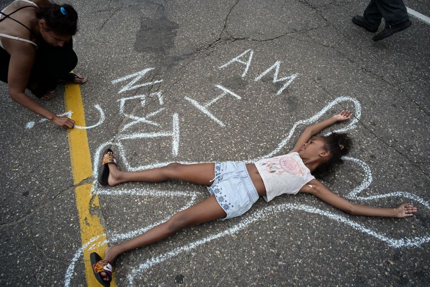 FILE - In this Thursday, July 7, 2016 file photo, Tia Williams, left, and her daughter Aissa create a display on the street outside the Minnesota governor's official residence in St. Paul, Minn., as people gathered to protest the shooting death of Philando Castile by police. Castile was shot and killed July 6, 2016 by officer Jeronimo Yanez, who is Hispanic, after being pulled over as he drove through a suburb of St. Paul, Minnesota, with his girlfriend and her young daughter in the car. Livestreaming on Facebook moments later, his girlfriend said Castile, 32, was shot while reaching for his ID after telling the officer he had a gun permit and was armed. Ramsey County Attorney John Choi concluded that Yanez wasn't justified in using deadly force. Yanez is charged with manslaughter and is free ahead of his trial scheduled to start later this month. (Richard Tsong-Taatarii/Star Tribune via AP)/Star Tribune via AP)