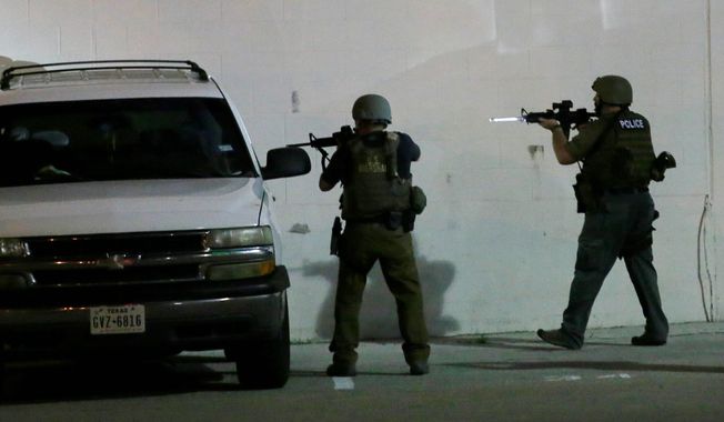 Police check a car early Friday, July 8, 2016, in Dallas, Snipers opened fire on police officers in Dallas on Thursday night; some of the officers were killed, police said. (AP Photo/LM Otero)