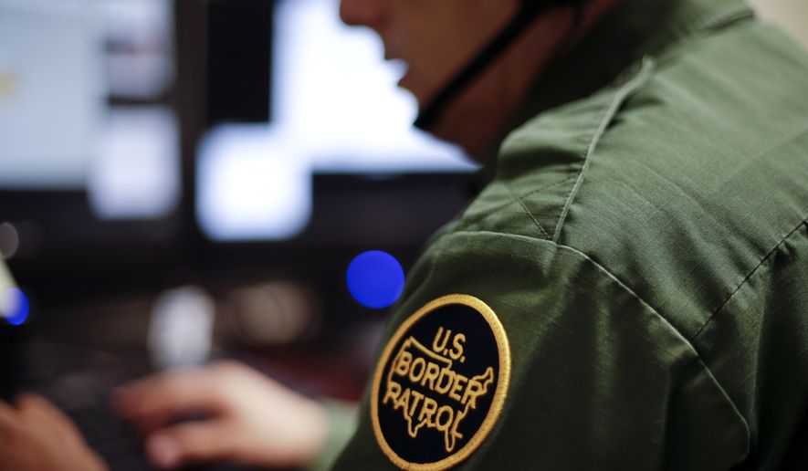In this June 5, 2014, file photo, a Border Patrol agent uses a headset and computer to conduct a long-distance interview by video from a facility in San Diego. (AP Photo/Gregory Bull, File)