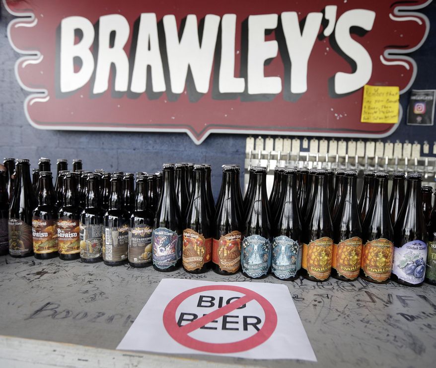 A sign against large beer companies is placed on the bar near bottles of Wicked Weed beer at Brawley's Beverage in Charlotte, N.C., Thursday, May 4, 2017. Brawley's is among at least a handful of stores or restaurants that announced they don't intend to stock Wicked Weed in the future.(AP Photo/Chuck Burton)