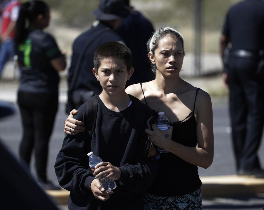 Christina Marquez, right, picks up her son Angelo Marquez at the scene of a school bus crash Thursday, May 4, 2017, in Las Vegas. Angelo Marquez was in a the school bus during the crash. (AP Photo/John Locher)