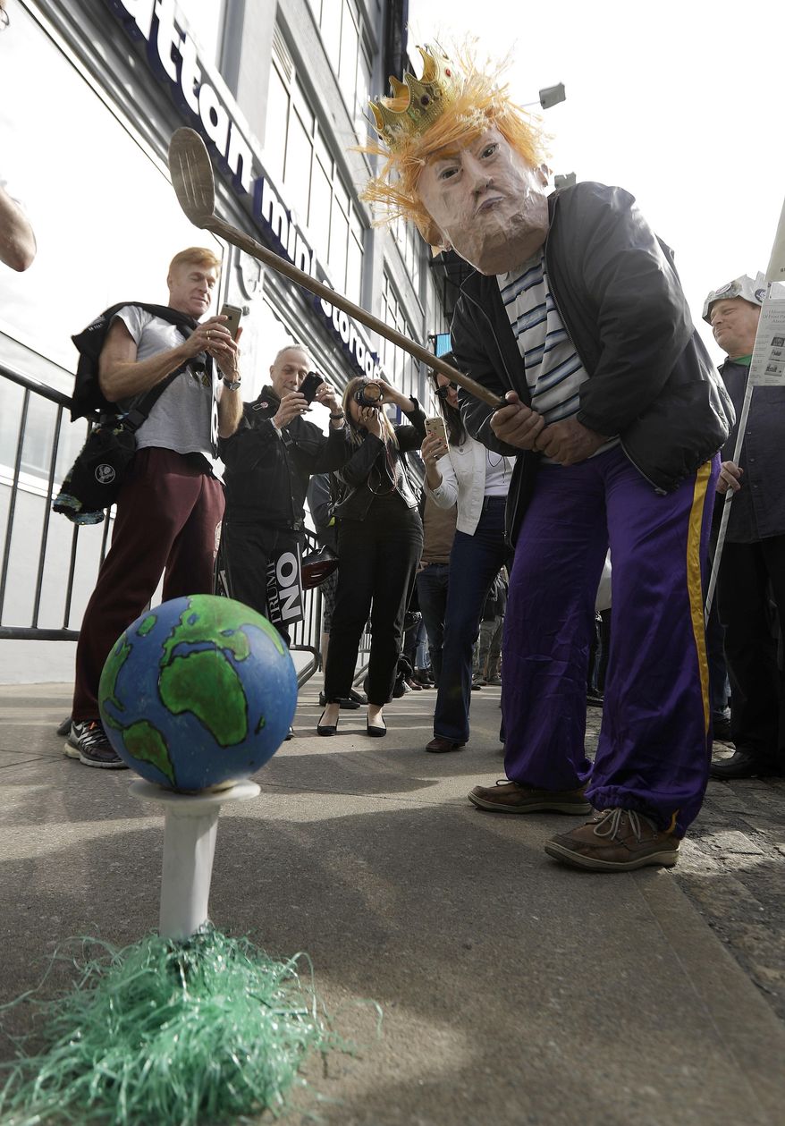 A man wearing a mask of President Donald Trump pretends to play golf with a prop during a protest across the street from the Intrepid Sea, Air & Space Museum, where President Trump is expected to attend the 75th Anniversary Battle of the Coral Sea Commemorative Dinner on the USS intrepid, Thursday, May 4, 2017, in New York. (AP Photo/Julio Cortez)