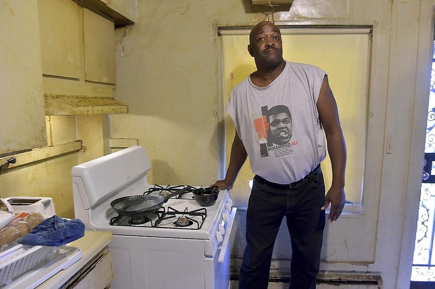 In this May 10, 2016 photo, Kenny Simelton talks about issues with his Elmwood apartment in Cairo, Ill. Simelton had pulled back the stove to show where rats have been getting in. A government plan to tear down the crumbling public housing complex in the southern Illinois town of Cairo has sent roughly 200 families searching for new homes and sparked fears that the once-thriving river city could be coming to an end. (Richard Sitler/The Southern Illinoisan via AP)
