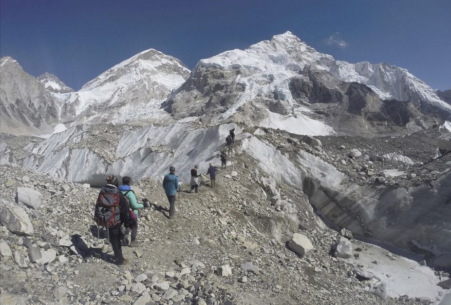 FILE - In this Feb. 22, 2016 file photo, international trekkers pass through a glacier at the Mount Everest base camp, Nepal. A Nepalese official says Sherpa workers are fixing the final route to the summit of Mount Everest and the first climb of the season could be days away. (AP Photo/Tashi Sherpa, file)