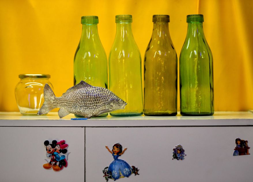 In this Thursday, May 4, 2017, photo Communist era milk bottles are on display along with a metal fish at the newly opened Bucharest Kitsch Museum, in Bucharest, Romania. The Kitsch Museum opens for visitors on Friday, May 5, 2017. (AP Photo/Vadim Ghirda)