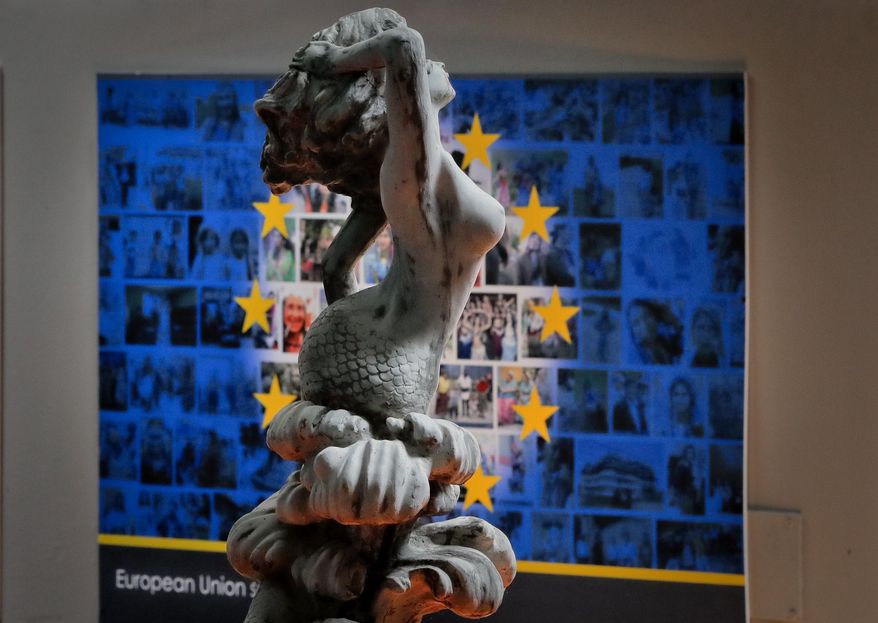 In this Thursday, May 4, 2017, photo a plaster statue is backdropped by an interpretation of the European Union flag at the newly opened Bucharest Kitsch Museum, in Bucharest, Romania. The Kitsch Museum opens for visitors on Friday, May 5, 2017. (AP Photo/Vadim Ghirda)