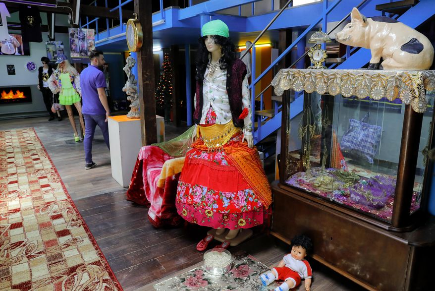 In this Thursday, May 4, 2017, a man walks by exhibits in the Gypsy kitsch section at the newly opened Bucharest Kitsch Museum, in Bucharest, Romania. The Kitsch Museum opens for visitors on Friday, May 5, 2017. (AP Photo/Vadim Ghirda)
