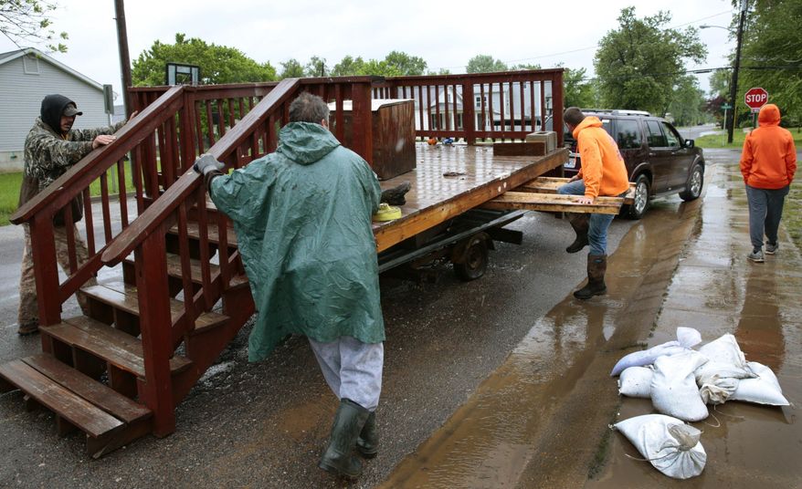 Friends of Charlie Christian, second from right, help move Christian's mobile home deck that floated away on to Second Street in downtown Pacific on Thursday, May 4, 2017. Pacific officials estimate 170 homes and businesses were flooded. (Robert Cohen/St. Louis Post-Dispatch via AP)