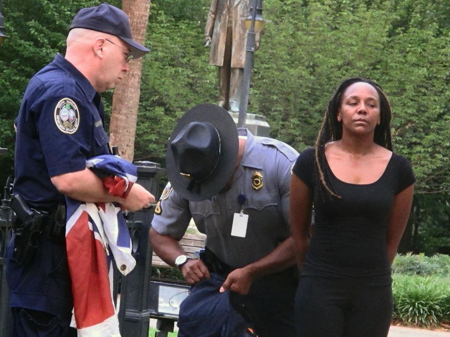 FILE - In this June, 27, 2015 file photo, Bree Newsome of Charlotte, N.C., right, is taken into custody after she removed the Confederate flag from a monument in front of the South Carolina Statehouse in Columbia, S.C., in the aftermath of the attack at a Charleston church where a white supremacist shot nine parishioners to death during a Bible study. Black women have not been strangers to past protests. But historians say they have often been overshadowed, first by white women during the suffragette movement and then by the black men who were lionized during the civil rights movement. (AP Photo/Bruce Smith, File)