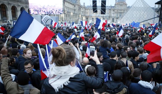People wave French flags at the Louvre museum where Emmanuel Macron is planning to celebrate, Sunday, May 7, 2017 in Paris.Thousands of supporters of French centrist candidate Emmanuel Macron have let out a big cheer when national television called the presidential election in his favor based on poll projections. (AP Photo/Francois Mori)
