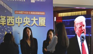 A projector screen shows a footage of U.S. President Donald Trump as workers wait for investors at a reception desk during an event promoting EB-5 investment in a Kushner Companies development at a hotel in Shanghai, China, Sunday, May 7, 2017. The sister of President Trump&#x27;s son-in-law, Jared Kushner, has been courting Chinese investors using a much-criticized federal visa program that provides a path toward obtaining green cards. (AP Photo)