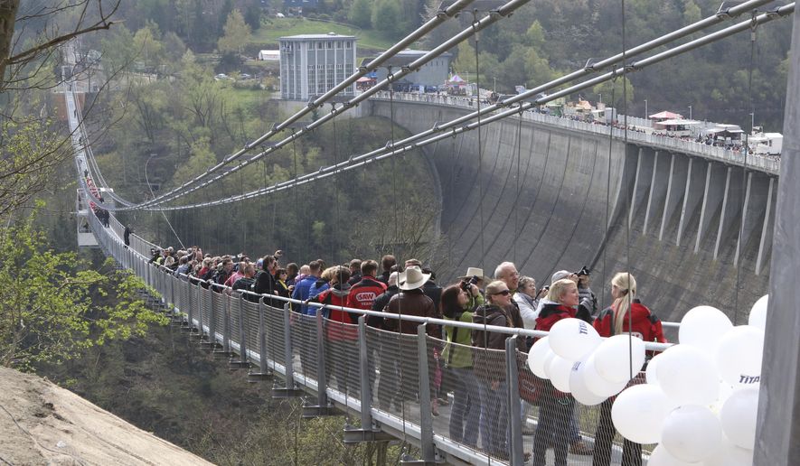 People walk across the newly opened cable suspension bridge at the Rappbode dam near Ruebeland, Germany, Sunday, May 7, 2017. According to the operators, the bridge is the longest pedestrian cable suspension bridge in the world. (Matthias Bein/dpa via AP)