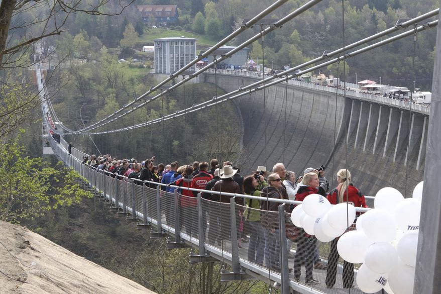 People walk across the newly opened cable suspension bridge at the Rappbode dam near Ruebeland, Germany, Sunday, May 7, 2017. According to the operators, the bridge is the longest pedestrian cable suspension bridge in the world. (Matthias Bein/dpa via AP)