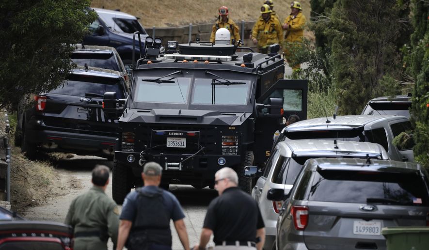 Investigators walk toward a SWAT truck Monday, May 8, 2017, in Los Angeles. Police have shot at a burglary suspect who has been barricaded in a Los Angeles home for several hours. (AP Photo/Jae C. Hong)