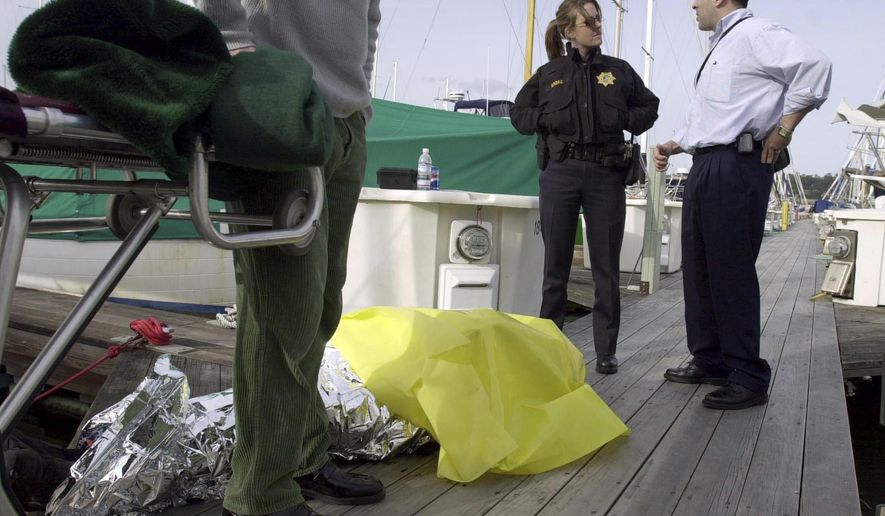 In this Feb. 28, 2004, photo, Sausalito police officer B. Baraz, back left, and then-Coroner Investigator Darrell Harris, right, prepare to move a body found at the yacht harbor in Sausalito, Calif. Harris has been arrested and charged with sexually abusing a girl younger than 14. He is scheduled to be arraigned Monday, May 8, 2107, on four felony charges and a misdemeanor count of sexually abusing the girl over the last nine years. (Jeff Vendsel/Marin Independent Journal via AP)