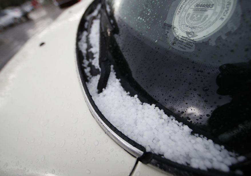 Hail collects at the base of the windshield of a vehicle as a spring storm, packing high winds, heavy rains and hail, sweeps over Colorado's Front Range just before the afternoon rush hour starts Monday, May 8, 2017, in Denver. (AP Photo/David Zalubowski)