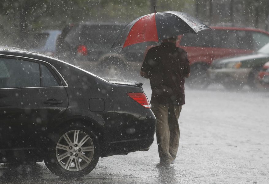 A motorist heads to his vehicle under the cover of an umbrella as a spring storm packing high winds, heavy rains and hail sweeps over Colorado's Front Range just before the afternoon rush hour starts Monday, May 8, 2017, in Denver. (AP Photo/David Zalubowski)