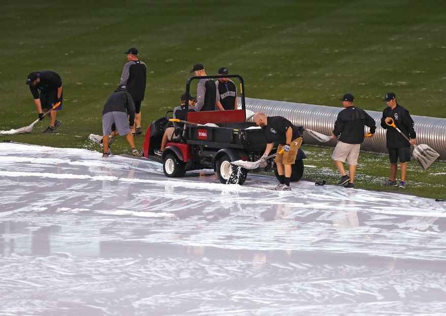 Coors Field grounds shovel hail off the tarp during a delayed baseball game between the Chicago Cubs and Colorado Rockies, Monday, May 8, 2017, in Denver. (AP Photo/ Jack Dempsey)