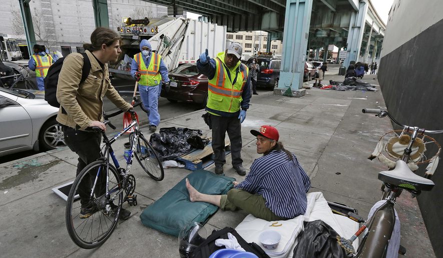 File - In this Feb. 26, 2016, file photo, a city worker tells a homeless man that the area next to him on is about to be power washed and points to an area he might want to move in San Francisco. A San Francisco-based nonprofit has pledged to raise $100 million to reduce chronic homelessness in the city by half over the next five years. (AP Photo/Eric Risberg, File)
