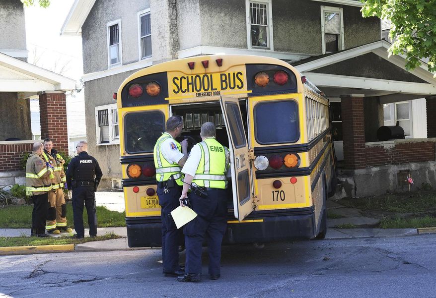 Rescue workers investigate at the scene where a Fort Wayne Community Schools bus ran into a home in Fort Wayne, Ind., Monday morning May 8, 2017. WANE-TV reported no students were aboard the bus when it collided with another vehicle and hit the home. (Cathie Rowand/The Journal-Gazette via AP)