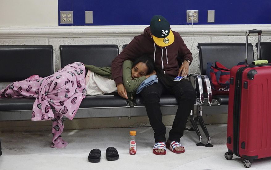 Latreece Smith rests as her friend Tamari Cameron checks flight information, Tuesday, May 9, 2017, at the Fort Lauderdale-Hollywood International Airport in Fort Lauderdale, Fla. Skirmishes involving irate passengers broke out at the Florida airport Monday following the cancellation of multiple Spirit Airlines flights. (Joe Cavaretta/South Florida Sun-Sentinel via AP)
