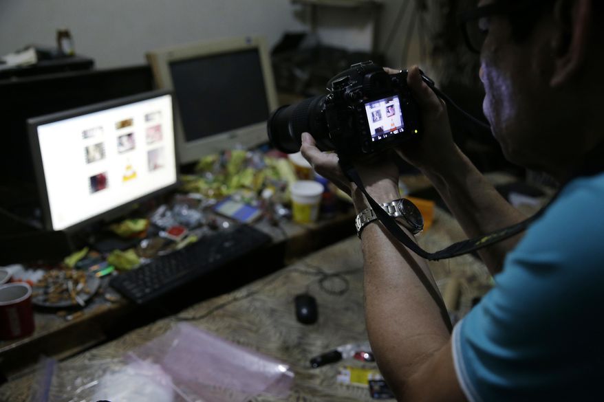 In this April 20, 2017, photo, a Filipino member of the National Bureau of Investigation takes a picture of the computer of suspected child webcam cybersex operator, David Timothy Deakin, from Peoria, Ill., during a raid at his home in Mabalacat, Philippines. Deakin's arrest reveals one of the darkest corners of the internet, where pedophiles in the U.S., Canada, Europe and Australia pay facilitators on the other side of the world to sexually abuse children, directing their moves through online livestreaming services. (AP Photo/Aaron Favila)
