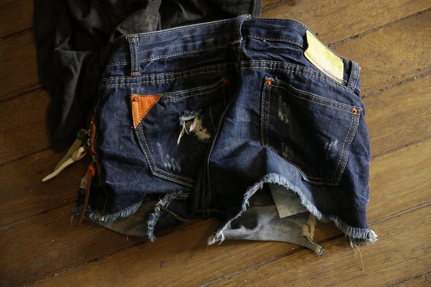 In this April 20, 2017, photo, a young girl's jean shorts are seen on the floor of the home of suspected child webcam cybersex operator, David Timothy Deakin, from Peoria, Ill., as investigators gather evidence during a raid in Mabalacat, Philippines. Children's underwear, toddler shoes, cameras, bondage cuffs, fetish ropes, meth pipes, stacks of hard drives and photo albums cluttered the stuffy, two-bedroom townhouse. In his computer files, there were videos and images of children engaged in sex acts. (AP Photo/Aaron Favila)