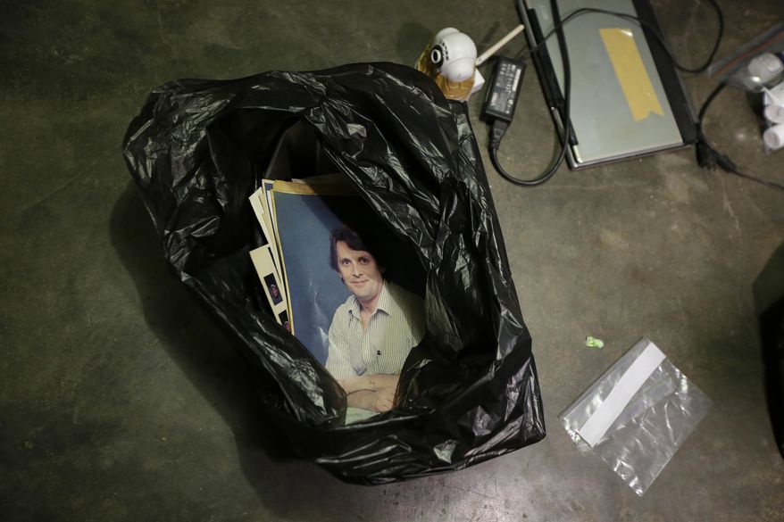 In this April 20, 2017, photo, a photograph of suspected child webcam cybersex operator, David Timothy Deakin, from Peoria, Ill., is seen besides a laptop computer and wireless web camera during a raid at his home in Mabalacat, Philippines. Deakin's arrest reveals one of the darkest corners of the internet, where pedophiles in the U.S., Canada, Europe and Australia pay facilitators on the other side of the world to sexually abuse children, directing their moves through online livestreaming services. (AP Photo/Aaron Favila)