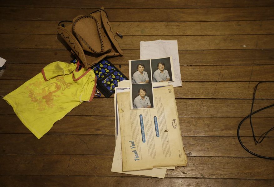 In this April 20, 2017, photo, a young girl's shirt, a cowboy hat and pictures of suspected child webcam cybersex operator, David Timothy Deakin, from Peoria, Ill., lay on the floor during a raid in Mabalacat, Philippines. Children's underwear, toddler shoes, cameras, bondage cuffs, fetish ropes, meth pipes, stacks of hard drives and photo albums cluttered the stuffy, two-bedroom townhouse. In his computer files, there were videos and images of young children engaged in sex acts. (AP Photo/Aaron Favila)
