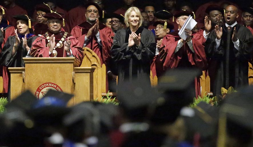 Bethune-Cookman University president Edison Jackson, left, and United States Secretary of Education Betsy DeVos applaud students as they are introduced during commencement exercises, Wednesday, May 10, 2017, in Daytona Beach, Fla. (AP Photo/John Raoux)