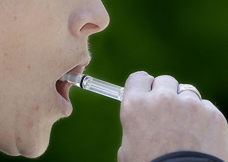 California Highway Patrol Sgt. Jaimi Kenyon, swabs the inside of her mouth to collect saliva during a demonstration of drug testing device Wednesday, May 10, 2017, in Sacramento, Calif. Three of California's largest counties are testing a device that can detect the presence of drugs in saliva within five minutes. Some officers and lawmakers want the devices used statewide after voters passed Proposition 64 in November, legalizing the recreational use of marijuana. (AP Photo/Rich Pedroncelli)