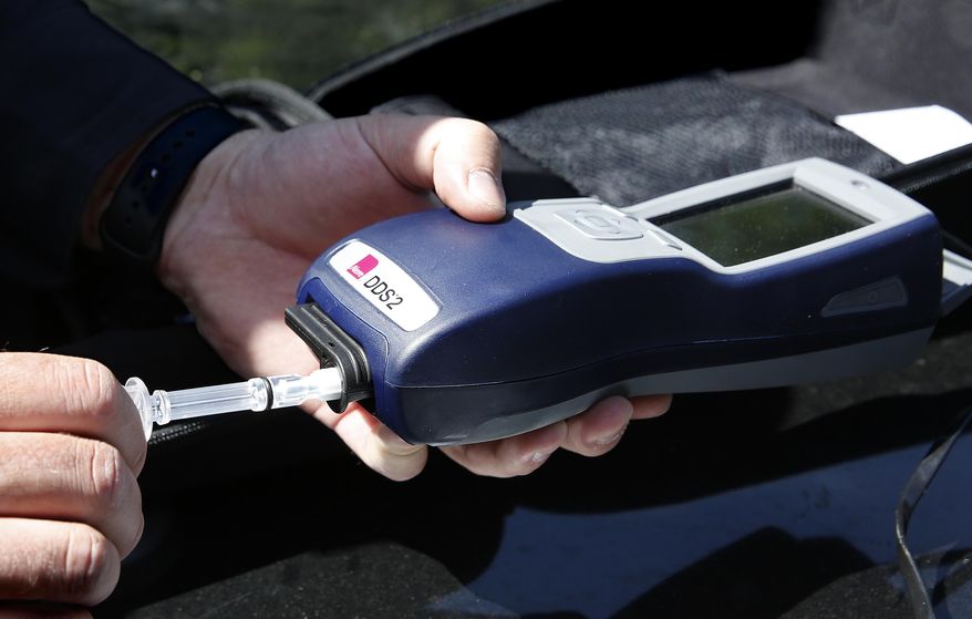 Sacramento Police Corporal Luke Moseley places a sample of saliva taken from another office pretending to be a driver suspected to be under the influence of drugs, during a demonstration of drug testing device Wednesday, May 10, 2017,in Sacramento, Calif. Three of California's largest counties are testing a device that can detect the presence of drugs in saliva within five minutes. Some officers and lawmakers want the devices used statewide after voters passed Proposition 64 in November, legalizing the recreational use of marijuana. (AP Photo/Rich Pedroncelli)