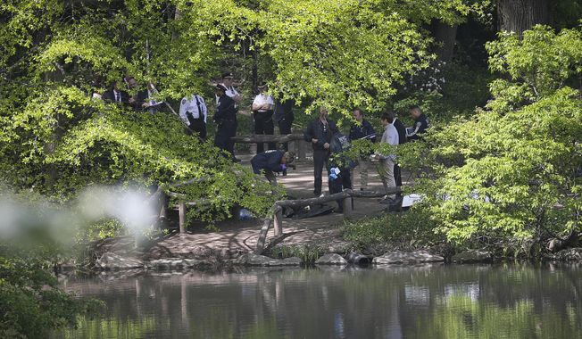 Medical examiner officials, center, take photos of a body pulled from a pond in Central Park, Wednesday May 10, 2017, in New York. The discovery came a day after the body of another man was recovered in the Jacqueline Kennedy Onassis Reservoir in the park. New York City police say the deaths of two men found in Central Park lakes don&#x27;t appear to be crime-related. (AP Photo/Bebeto Matthews)