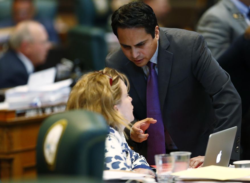 Colorado State Rep. Dan Pabon, D-Denver, back, confers with Rep. KC Becker, D-Boulder, during debate on a measure on the floor of the House during the body's closing session Wednesday, May 10, 2017, in Denver. Colorado lawmakers are concluding business for the year with hard-fought agreements on highways, hospitals and affordable housing. (AP Photo/David Zalubowski)