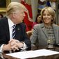 FILE - In this Tuesday, Feb. 14, 2017 file photo, President Donald Trump looks at Education Secretary Betsy DeVos as he speaks during a meeting with parents and teachers in the Roosevelt Room of the White House in Washington. A schism between wealthy funders over private-school vouchers became visible in 2017 during the confirmation process for DeVos, a billionaire heiress who was nominated by Trump for education secretary despite having no experience as a teacher or school administrator. DeVos attended private religious schools in Michigan. Her children were homeschooled and attended religious schools.  (AP Photo/Evan Vucci)