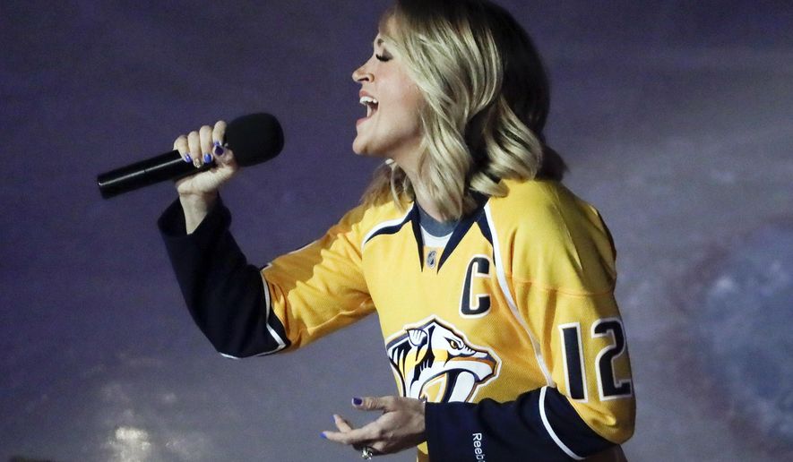 FILE - In this April 17, 2017, file photo, country music star Carrie Underwood performs the national anthem before Game 3 of a first-round NHL hockey playoff series between the Predators and the Chicago Blackhawks, in Nashville, Tenn. Underwood is the wife of Predators center Mike Fisher. The town known as Music City has grabbed hold of the Nashville Predators with stars lining up to sing the national anthem or sing with the house band. Reaching the first Western Conference final in franchise history is spreading hockey fever far beyond the arena walls and the team’s loyal fans, sprouting Predators’ flags on front porches with upcoming opponents televised at barbecue joints.  (AP Photo/Mark Humphrey, File)