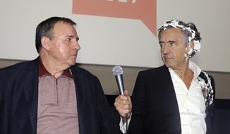 French philosopher and author Bernard-Henri Levy, right, holds a microphone after being struck in the face with a pie by leftist activists during the presentation of his documentary with Serbian movie director Goran Markovic, in Belgrade, Serbia, Wednesday, May 10, 2017. Bernard-Henri Levy, known for his criticism of Serbian nationalist policies during the 1990s Balkan wars, is in Belgrade for the showing of his film about the Kurds&#39; battle against the Islamic State group. (AP Photo)
