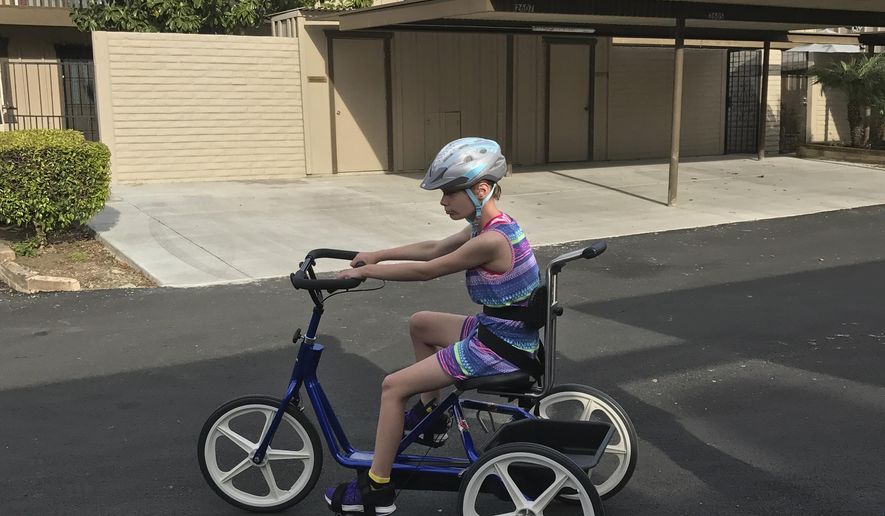 In this April 11, 2017 photo courtesy of Cate Luther shows her 12-year-old daughter, Charlotte Luther riding her found adaptive tricycle in Antioch, Calif. A Northern California police officer's dogged determination has reunited a special needs girl with her specially built tricycle. Antioch Police officer Dan Fachner recently arrested a 24-year-old man discovered riding the $4,000 tricycle late Tuesday. Fachner returned the trike to the family soon after arresting the suspect for theft. Antioch is 45 miles east of San Francisco. (Cate Luther via AP)