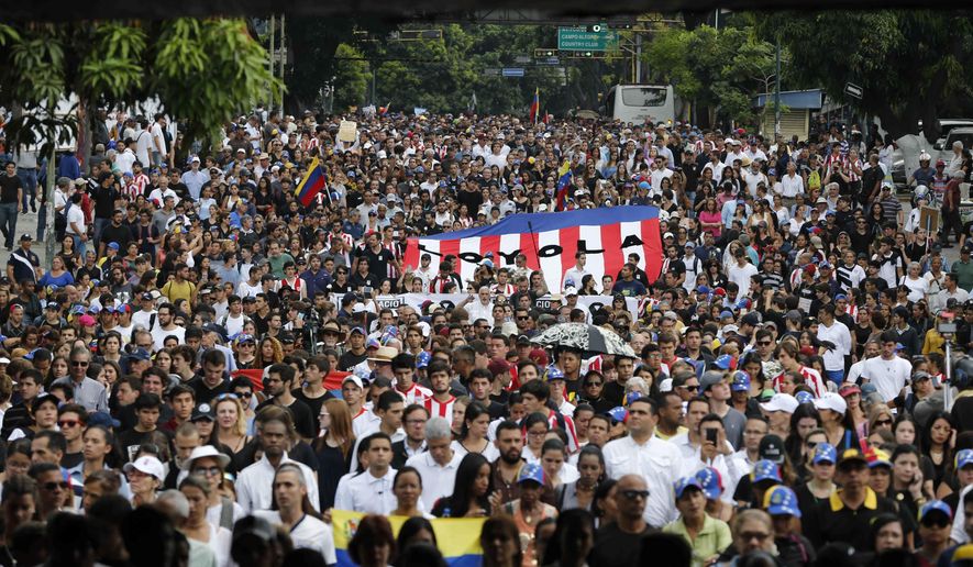 People gather for a homage to Miguel Castillo at the spot where he died yesterday in Caracas, Venezuela, Thursday, May 11, 2017. Castillo, 27, was killed during an anti-government protest when security forces dispersed thousands of people marching to the Supreme Court to reject a government initiative to rewrite the constitution. (AP Photo/Ariana Cubillos)