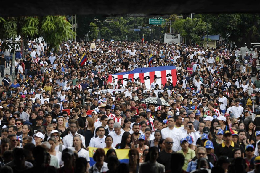 People gather for a homage to Miguel Castillo at the spot where he died yesterday in Caracas, Venezuela, Thursday, May 11, 2017. Castillo, 27, was killed during an anti-government protest when security forces dispersed thousands of people marching to the Supreme Court to reject a government initiative to rewrite the constitution. (AP Photo/Ariana Cubillos)