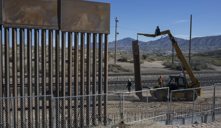 In this March 30, 2017 file photo, Workers use a crane to lift a segment of a new fence into place on the U.S. side of the border with Mexico, where Sunland Park, New Mexico, meets the Anapra neighborhood of Ciudad Juarez, Mexico, As President Donald Trump's administration fights to fund a new, multibillion-dollar border wall, government lawyers are still settling claims with Texas landowners over the fence Congress approved more than a decade ago. (AP Photo/Rodrigo Abd)