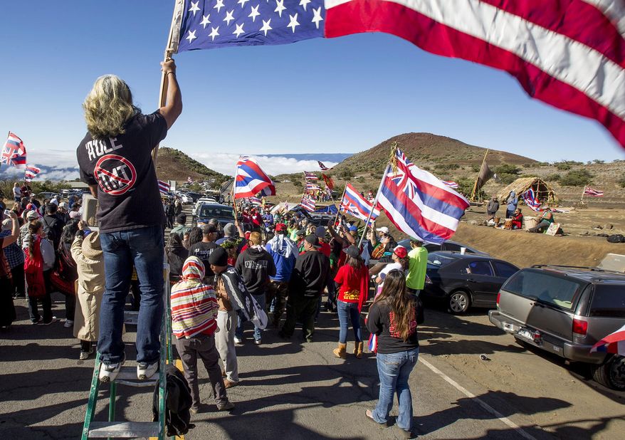 FILE - In this June 24, 2015, file photo, Thirty Meter Telescope protesters walk on a road during the first of many blockades that started at the Mauna Kea visitors center, stopping TMT construction vehicles from driving up to the summit of the mountain, about 40 miles west of Hilo, Hawaii. Some opponents of a giant telescope planned for the Hawaii mountain say they are at a disadvantage because they can't afford to pay for thousands of pages of transcripts from hearings to determine whether the project should be granted a construction permit. (Hollyn Johnson/Hawaii Tribune-Herald via AP, File)