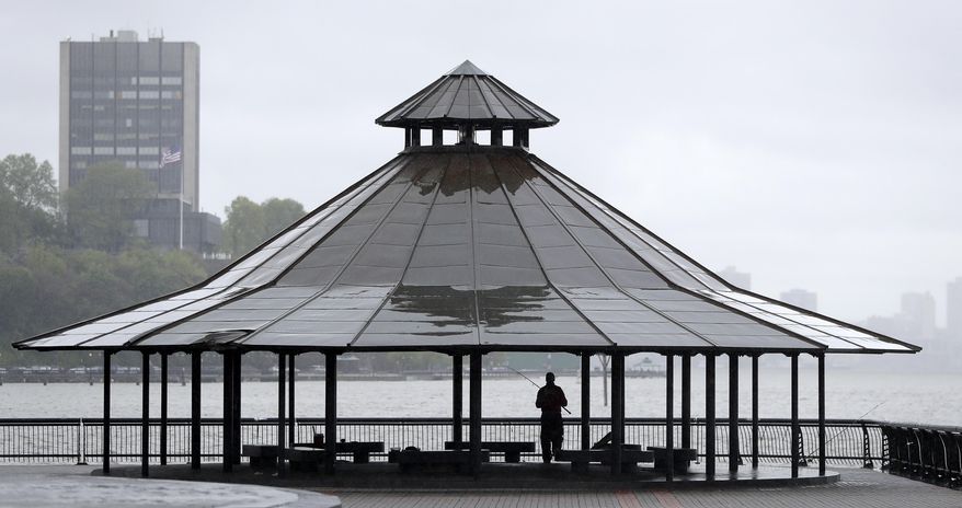 An angler takes shelter from the rain while fishing off Pier A Park, Saturday, May 13, 2017, in Hoboken, N.J. (AP Photo/Julio Cortez)