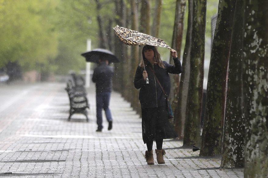 A woman controls the canopy of her umbrella in strong winds during a rainy day, Saturday, May 13, 2017, in Hoboken, N.J. (AP Photo/Julio Cortez)