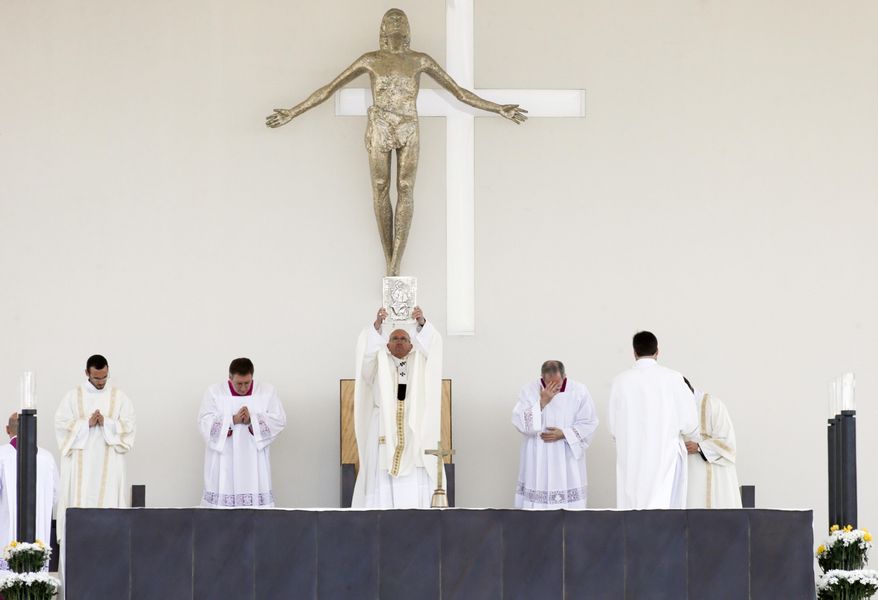 Pope Francis holds up the Gospel Book during an open-air solemn Mass to canonize Jacinta and Francisco Marto, at the Sanctuary of Our Lady of Fatima, Saturday, May 13, 2017, in Fatima, Portugal. Pope Francis urged Catholics on Friday to "tear down all walls" and spread peace as he traveled to this Portuguese shrine town to canonize two poor, illiterate shepherd children whose visions of the Virgin Mary 100 years ago marked one of the most important events of the 20th-century Catholic Church. (AP Photo/Armando Franca)