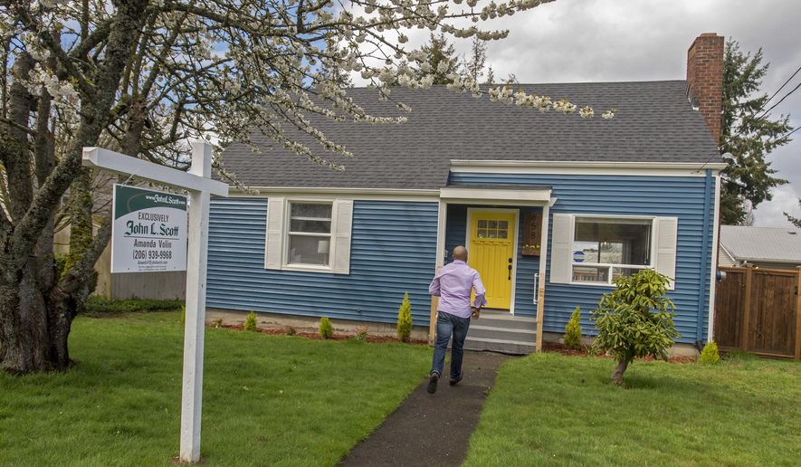 In this April 20, 2017 photo, real estate broker James Pitts III walks up to the fully remodeled childhood home of serial murderer Ted Bundy in Tacoma, Wash. The little blue house was built in 1946, the same year Bundy was born in Vermont. The Bundy family moved into the home in 1955, records show. (Peter Haley/The News Tribune via AP)