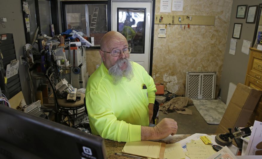 In this April 27, 2017 photo, George Hill talks with a visitor in the office of his tow-truck business in Long Beach, Wash. Hill was with Scott Johnson, who was a Washington state trooper at the time, when Johnson was shot as he and Hill were impounding a van that had been driven by a woman arrested for drunken driving. Johnson is now the Pacific County Sheriff, and attorneys for the man convicted in the shooting are seeking a new trial. (AP Photo/Ted S. Warren)