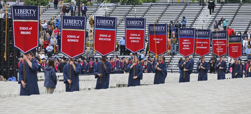 Liberty University graduates carry banners as they march into the stadium at the start of commencement ceremonies at the school in Lynchburg, Va., Saturday, May 13, 2017. (AP Photo/Steve Helber)