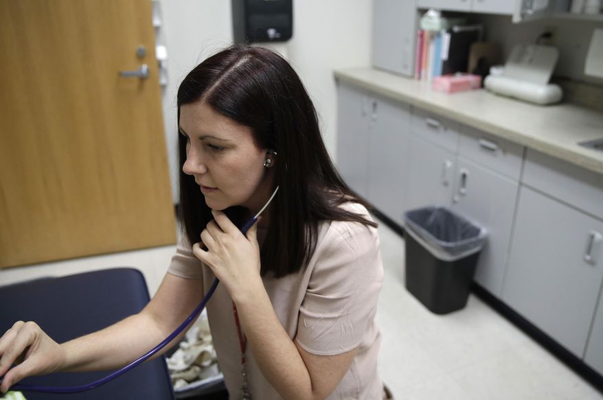 In this May 12, 2017, photo, registered nurse Samantha Marz checks a student at Rundle elementary school in Las Vegas. The Medicaid changes being advanced as part of the health overhaul are sounding familiar alarms for school districts still getting their financial footing after the Great Recession. (AP Photo/John Locher)